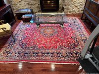 Full view of rug showing pattern, colors, and glass coffee table for scale.