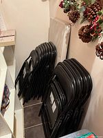 Stack of black padded folding chairs next to folded table