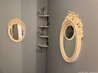 Both cream oval mirrors mounted on grey wall