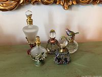 Front view of all five ornate glass perfume bottles