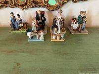 Five of the six Norman Rockwell figurines lined up on tabletop