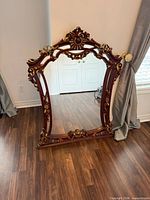 Front view of ornate carved wood mirror showing entire frame and mirror surface