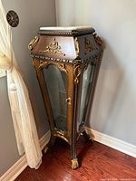 Front and side view of cabinet showing marble top, gilt details, glass panels