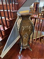 front view of ornate pedestal stand beside staircase