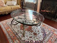 Full view of oval glass coffee table on rug