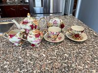 Front view of entire tea set showing teapot, creamer, sugar bowl, two cups and saucers