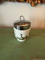 Front view of porcelain egg coddler with bird and pine decoration