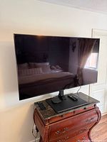 Front view of Sony 65" TV on stand with remotes and power cord visible