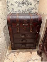Front view showing faux leather, three drawers, straps and hardware