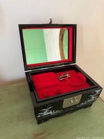 Open jewellery box showing red velvet interior, mirror, compartments