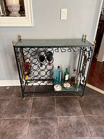 Front view of metal wine rack table showing granite top, bottle storage rings, stemware rack, and lower shelf