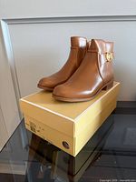 Pair of tan Michael Kors ankle boots on box
