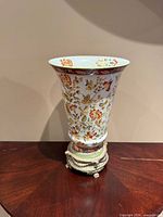 Full view of porcelain vase on metal base front profile