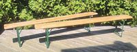 Two long wood-top benches with green folding legs on deck