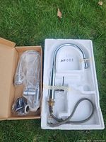 Both boxed faucets: gooseneck model in foam tray and flexible-neck model with hardware