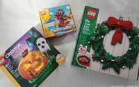 All three LEGO set boxes laid out: Creator Halloween Pumpkin 40697, Chinese New Year Dragon 40611, Christmas Wreath 40426