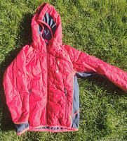 Red hooded quilted Vaude jacket displayed on grass