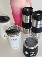 Front view of all six drinkware items showing branding and lids