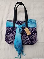Front view of batik tote with blue scarf and hang tag visible