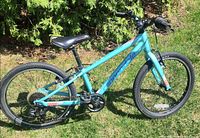 Full right-side view of Cannondale teal kids bike on grass