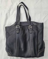 Front view of black leather Coach tote bag showing overall design and straps
