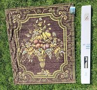 Front view of floral still-life tapestry next to box for scale