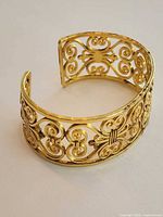 Full view of gold-tone filigree open cuff bracelet upright