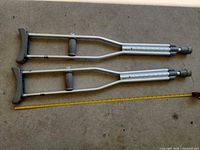 Pair of aluminum crutches with tape measure for scale