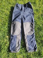 Full view of Vaude rain pants showing reinforced knees and elastic cuffs