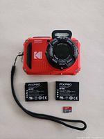Front of red Kodak PIXPRO WPZ2 camera with two LB-015 batteries and microSD card shown