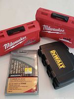 Overall view: two Milwaukee red cases, one DeWalt black case, Benchmark drill bit set package