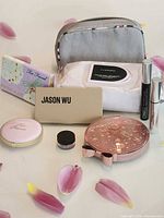 Group shot of all items: palettes, bronzer, wipes, mascaras, glitter jar and cosmetic bag