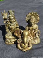 Three bronze figures: standing Shiva with trident, seated Hanuman, seated Ganesha