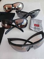 Four pairs sunglasses with cloth and pouches displayed
