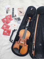 Violin in open case with bow and scattered accessories