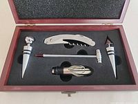 Open presentation box showing corkscrew, pourer, thermometer and two stoppers in foam insert