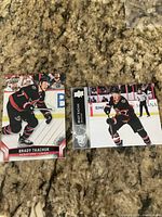 Two Brady Tkachuk Upper Deck hockey trading cards displayed on countertop