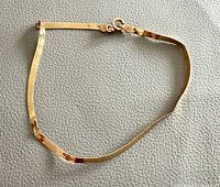 Full view of 10K gold bracelet laid flat showing length, clasp and herringbone links