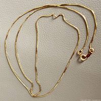 Full view of yellow gold chain laid out showing clasp and link style