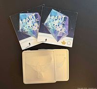 Overview of two Heart of the Arctic booklets and two square Millennium Keepsake metal cases