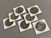 Seven Eisenhower dollar coins in cardboard flips
