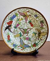 Front angled view of porcelain plate showing overall Thousand Butterfly design and gilt rim