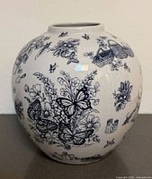 Front view of spherical blue on white ceramic vase with gardening illustrations