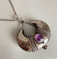 Front view of sterling silver crescent pendant with amethyst cabochon on chain