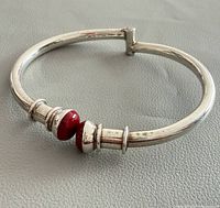 Full view of closed sterling silver bangle with coral cabochons