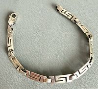 Full view of bracelet laid flat showing Greek key links and clasp