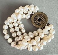 Bracelet coiled to show four strands of pearls and coin clasp
