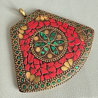 front view showing red and green stone mosaic on brass pendant