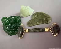 All four stone items grouped: two Buddha figurines, gua sha, facial roller
