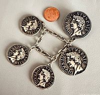 Full view of brooch with five linked replica coins alongside coin for scale